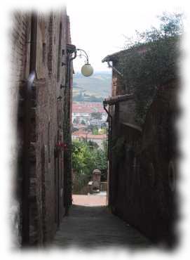 Gasse in Montereggioni mit Ausblick in die toskanische Landschaft