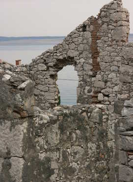 Das Meer durch eine leere Fensteröffnung einer alten Hausmauer