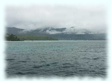 Die wolkenverhangene Insel Mahé, links im Vordergrund ein Teil der Île Ronde und dahinter die Île au Cerf