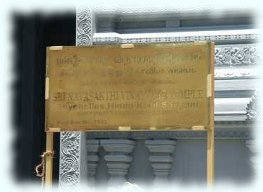 Goldfarbenes Schild vor dem Hindu-Tempel von Victoria mit Name und Adresse des Tempels in Sanskrit(?) und Englisch