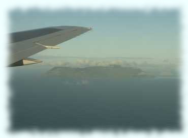Flügel des Flugzeuges und die wolkenverhangene Insel Silhoutte im Indischen Ozean