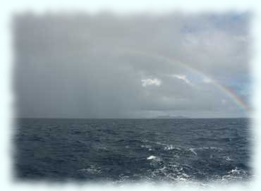 Blick Richtung Curieuse mit einem Regenbogen vor grauem Himmel