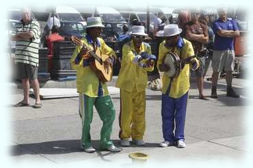 Eine Clowngruppe musiziert auf der Mole bei der Rückkehr von der Bootsausfahrt