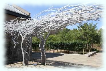 stilisierter Olivenbaum aus Metall am Eingang zum Restaurant