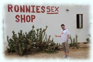 Rana vor der Mauer mit der Aufschrift 'Ronnies Sex Shop'