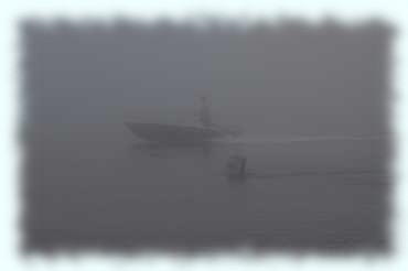Boje und Motorboot im Nebel