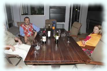 Attila, Paul und Regina am Tisch auf der Terrasse mit Rotweinflaschen