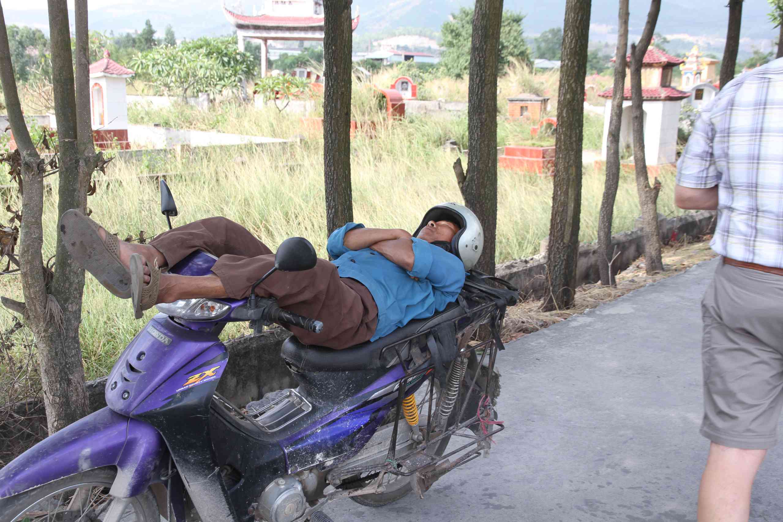 Ein Mann schläft auf seinem Moped