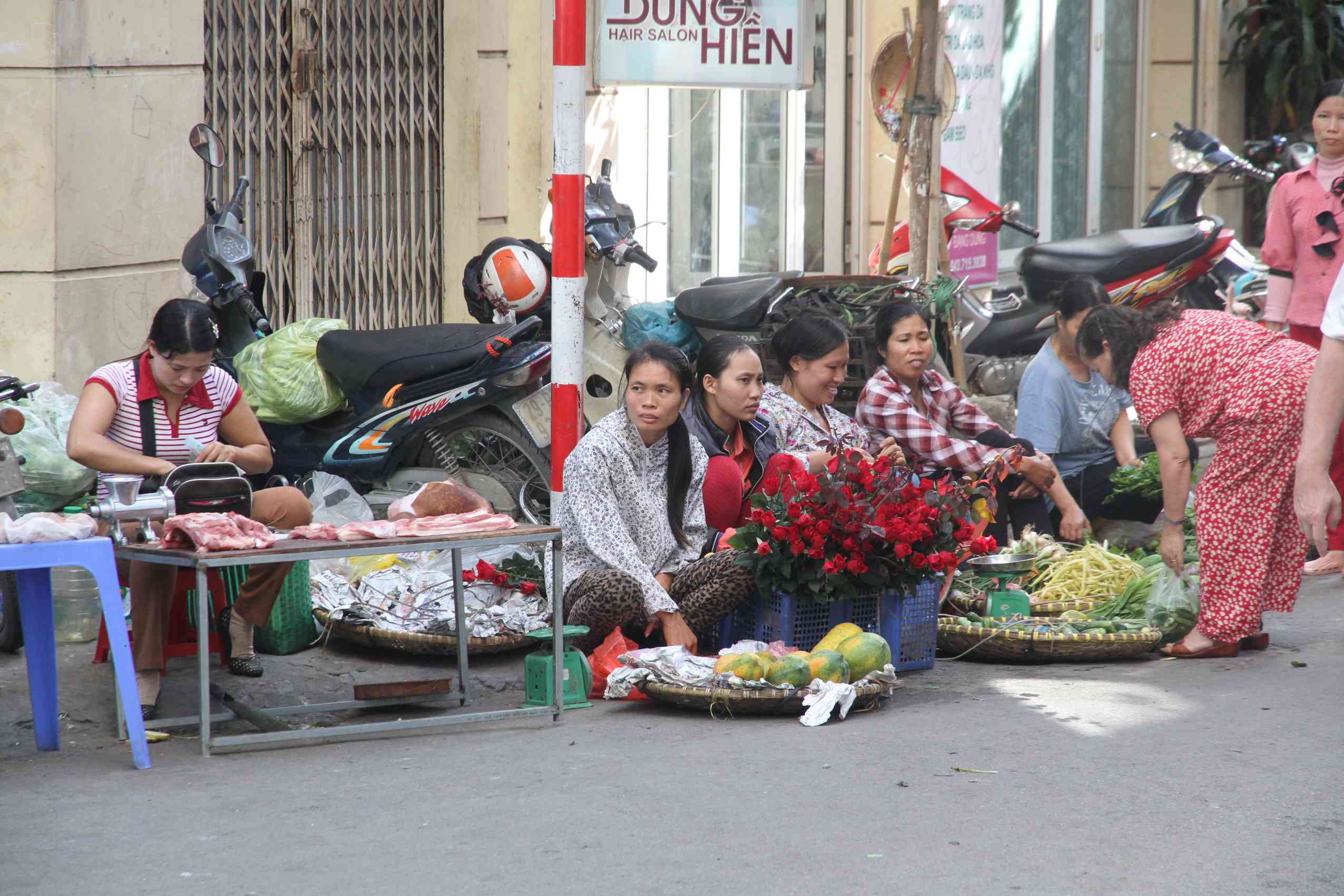 Strassenszene aus Hanoi mit Blumenverkäuferinnen am Strassenrand