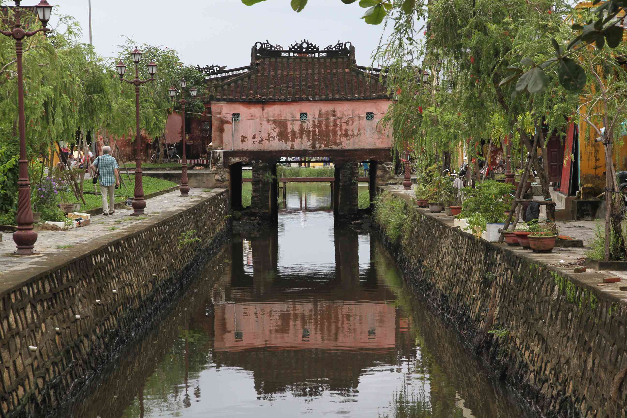 Kanal in der Altstadt von Hoi An mit einer überdachten Fußgängerbrücke im Hintergrund