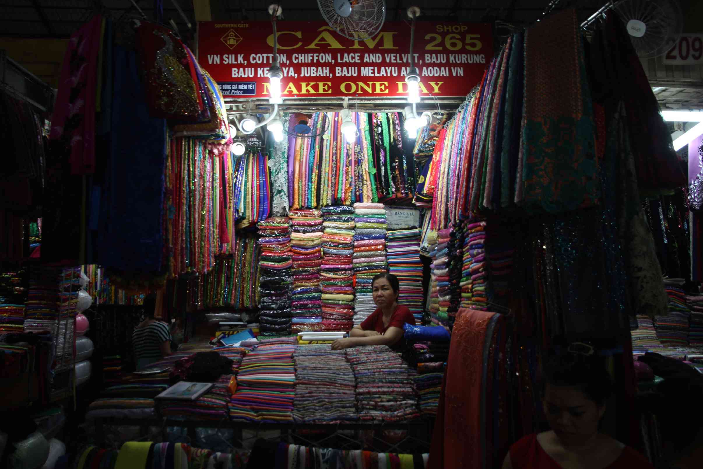 Ein Frau sitzt vor ihrem Marktstand mit Schals
